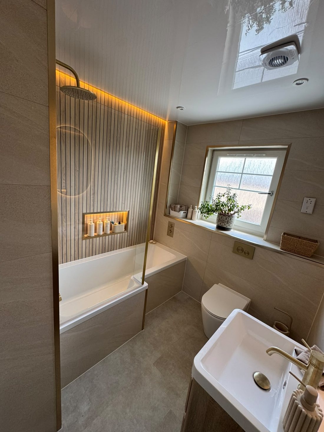 Cove-lit family bathroom with gold shower screen